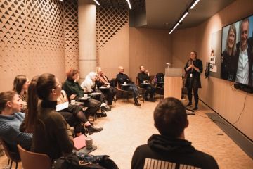 Fotka ukazuje skupinovou diskuzi v malém kruhu asi 12 lidí